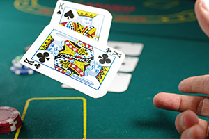 Bild eines Pokertisches, auf den gerade zwei Karten (Könige) abgeworfen werden